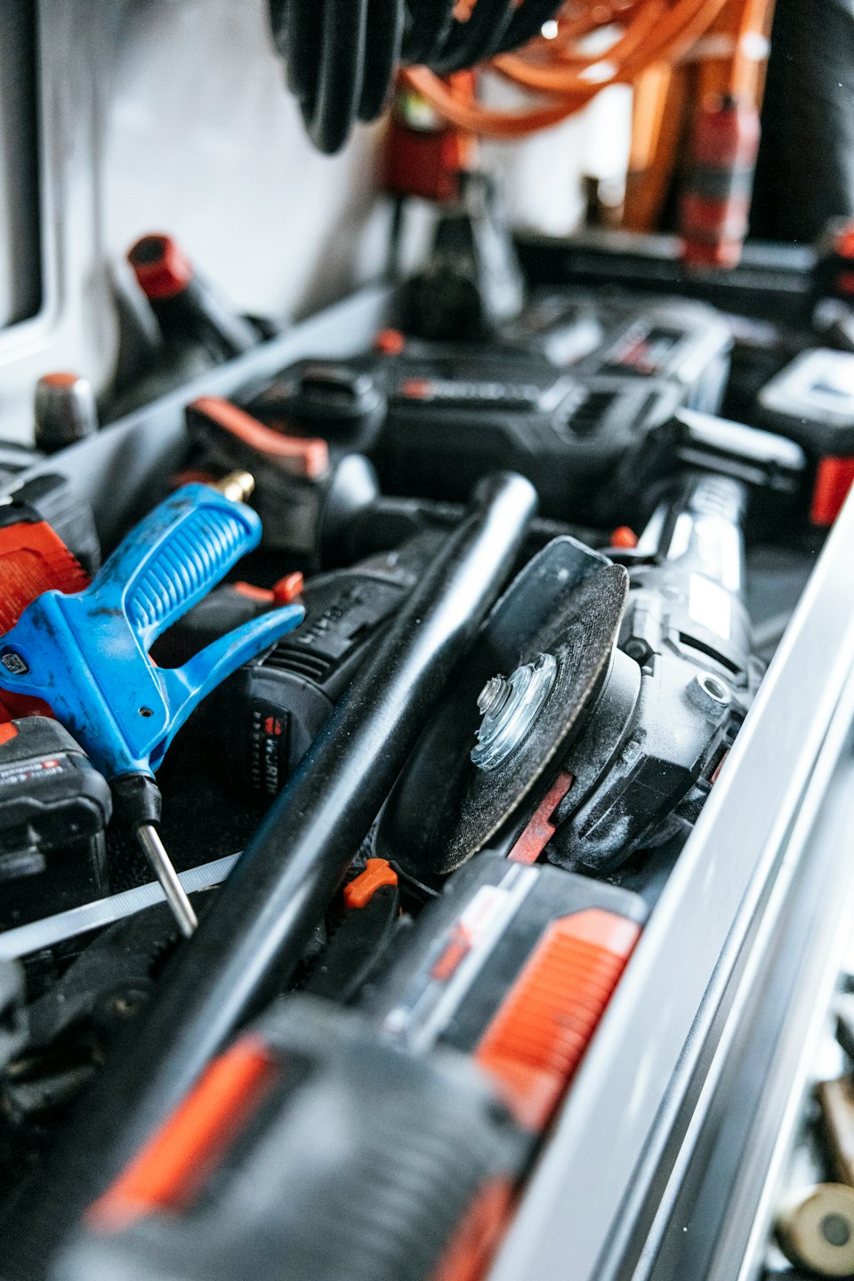 Messy toolbox drawer filled with power tools and accessories.