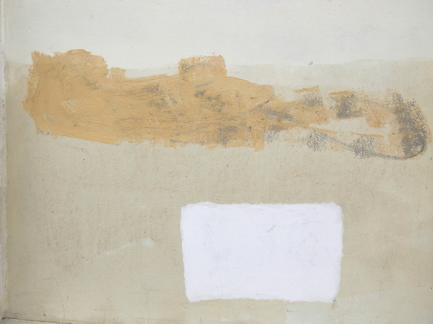 Textured beige wall with multiple patches of fresh paint.